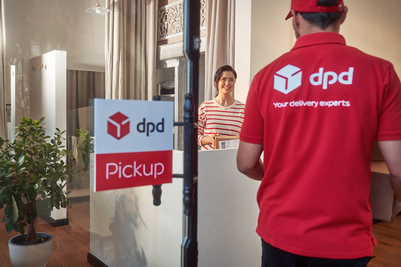 Kurier DPD odbiera paczkę od klientki w punkcie Pickup. Oznakowany punkt odbioru.